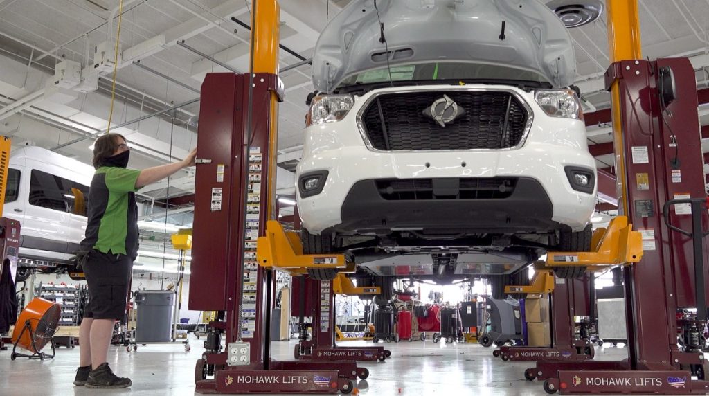 A technician lifts a Lightning Electric Transit van for final assembly