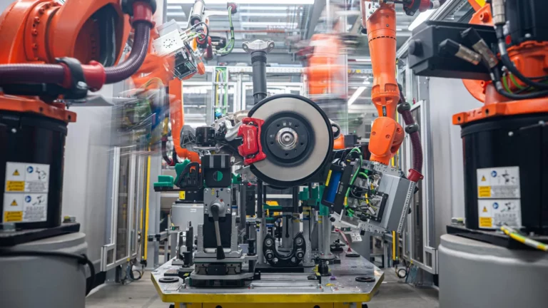 Automated end-of-line axle inspection cell at the Porsche Leipzig plant, with robotic arms scanning a finished axle assembly.