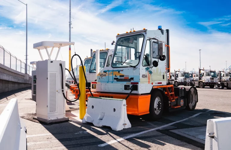 Orange EV battery-electric terminal tractor charging at APM Terminals Los Angeles Pier 400