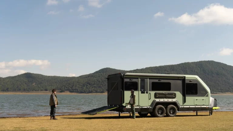 Evotrex-PG5 electric RV trailer parked lakeside with deployed patio during off-grid camping