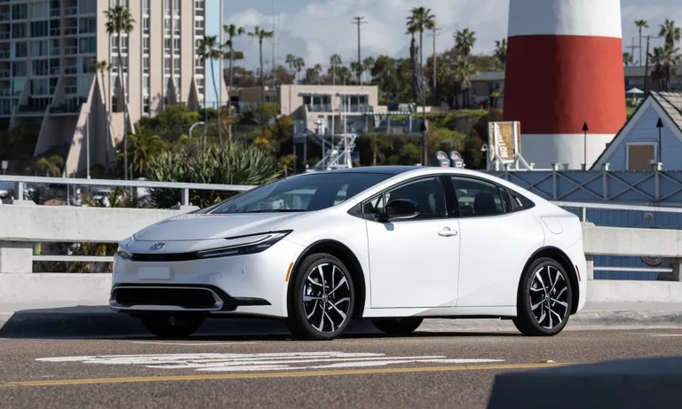 2027 Toyota Prius Plug-in Hybrid in white parked near a coastal boardwalk