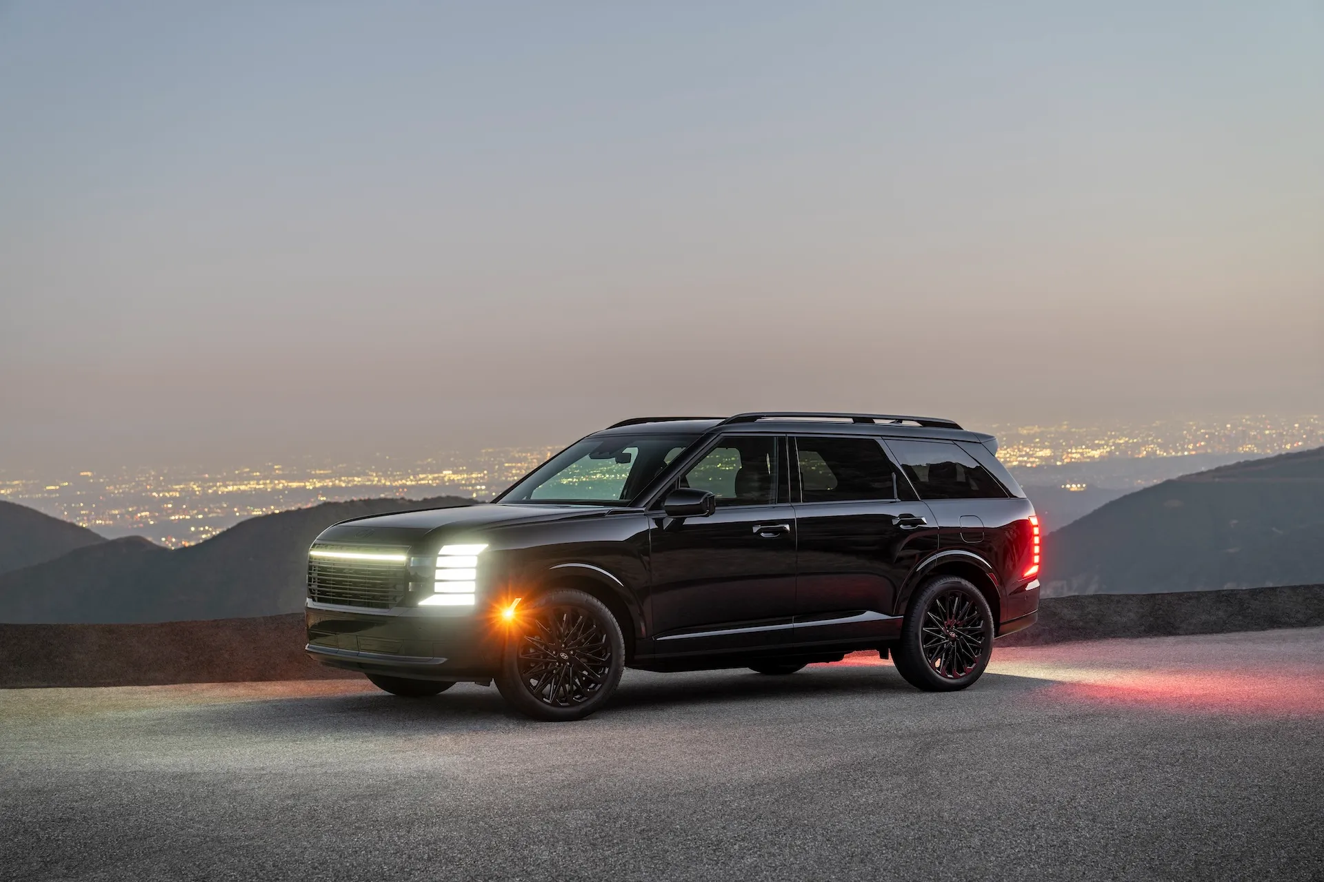 2027 Hyundai Palisade Hybrid Calligraphy Black Ink SUV parked overlooking city skyline at dusk