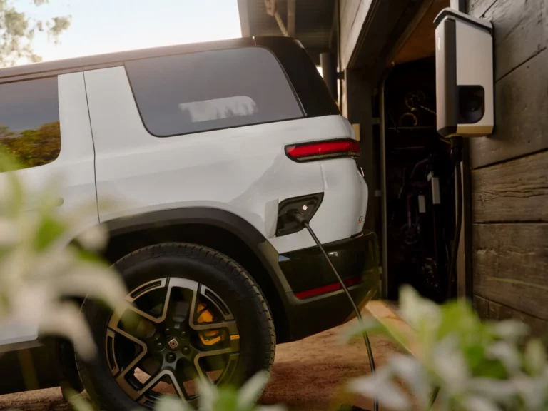 Rivian R2 electric SUV parked at a home charging setup in a residential driveway