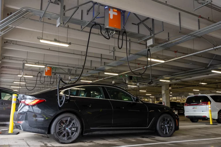 ChargePoint overhead EV charging dispensers with retractable cable management above rental vehicles at Portland International Airport's Quick Turnaround facility