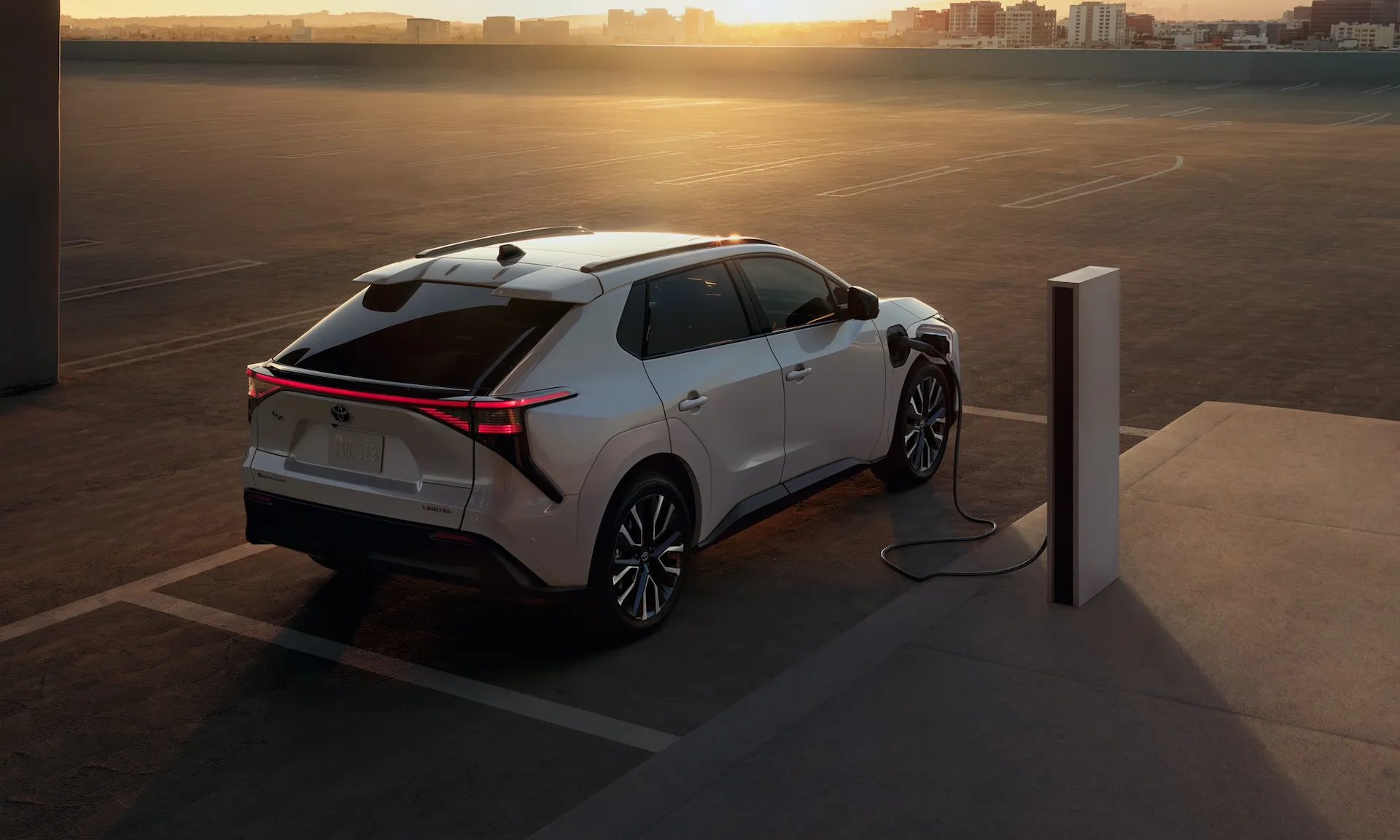 2027 Toyota bZ battery electric SUV charging at a public station at dusk