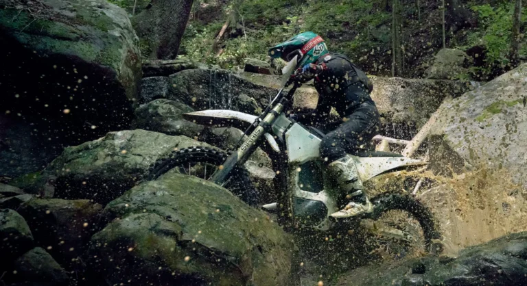Bonnell 805 RX electric dirt bike jumping over a hillside off-road trail with rider in full protective gear
