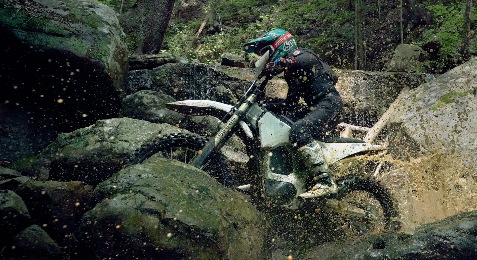 Bonnell 805 RX electric dirt bike jumping over a hillside off-road trail with rider in full protective gear