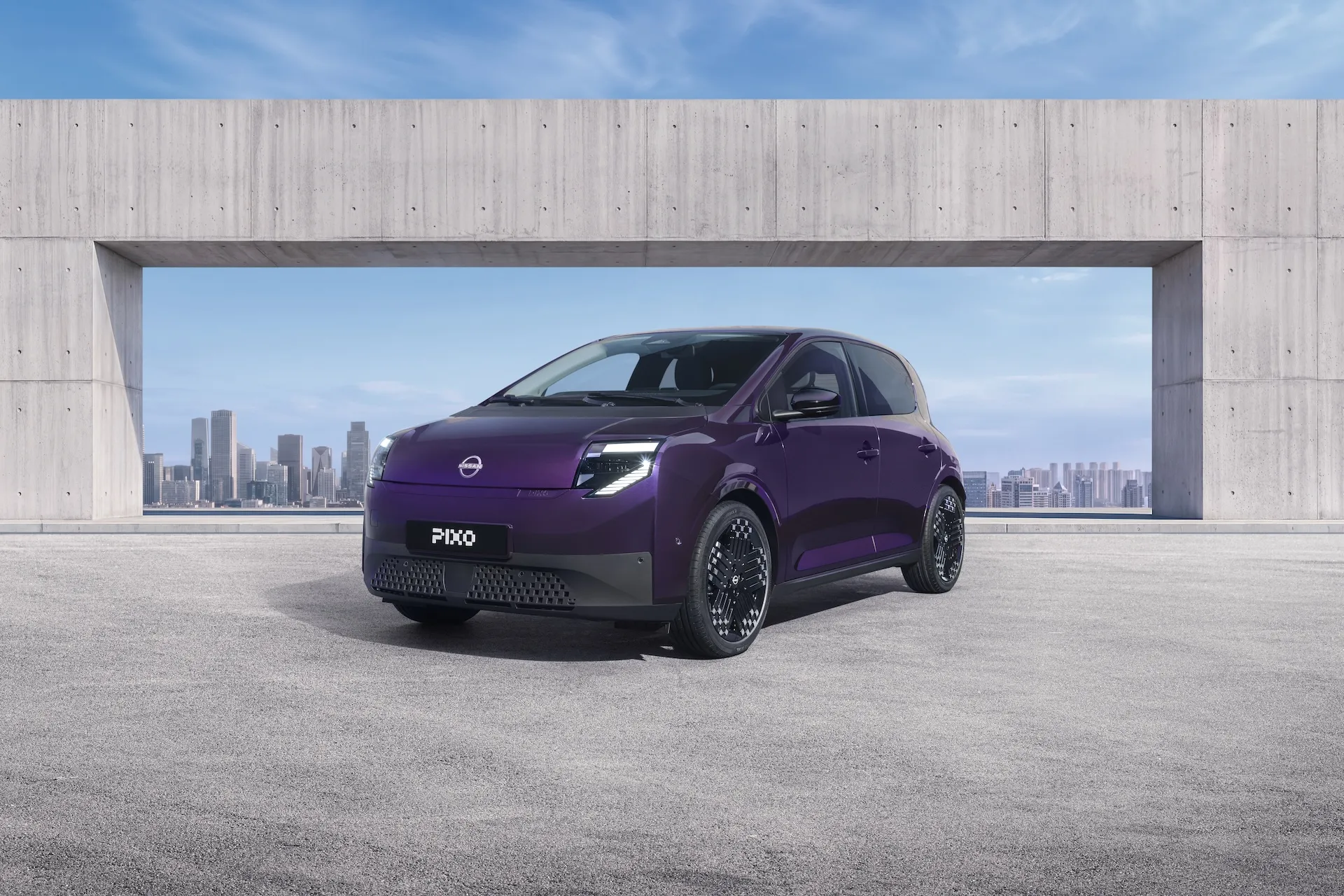 Three-quarter front view of a purple Nissan PIXO electric city car parked beneath a modern concrete structure with a city skyline behind it.