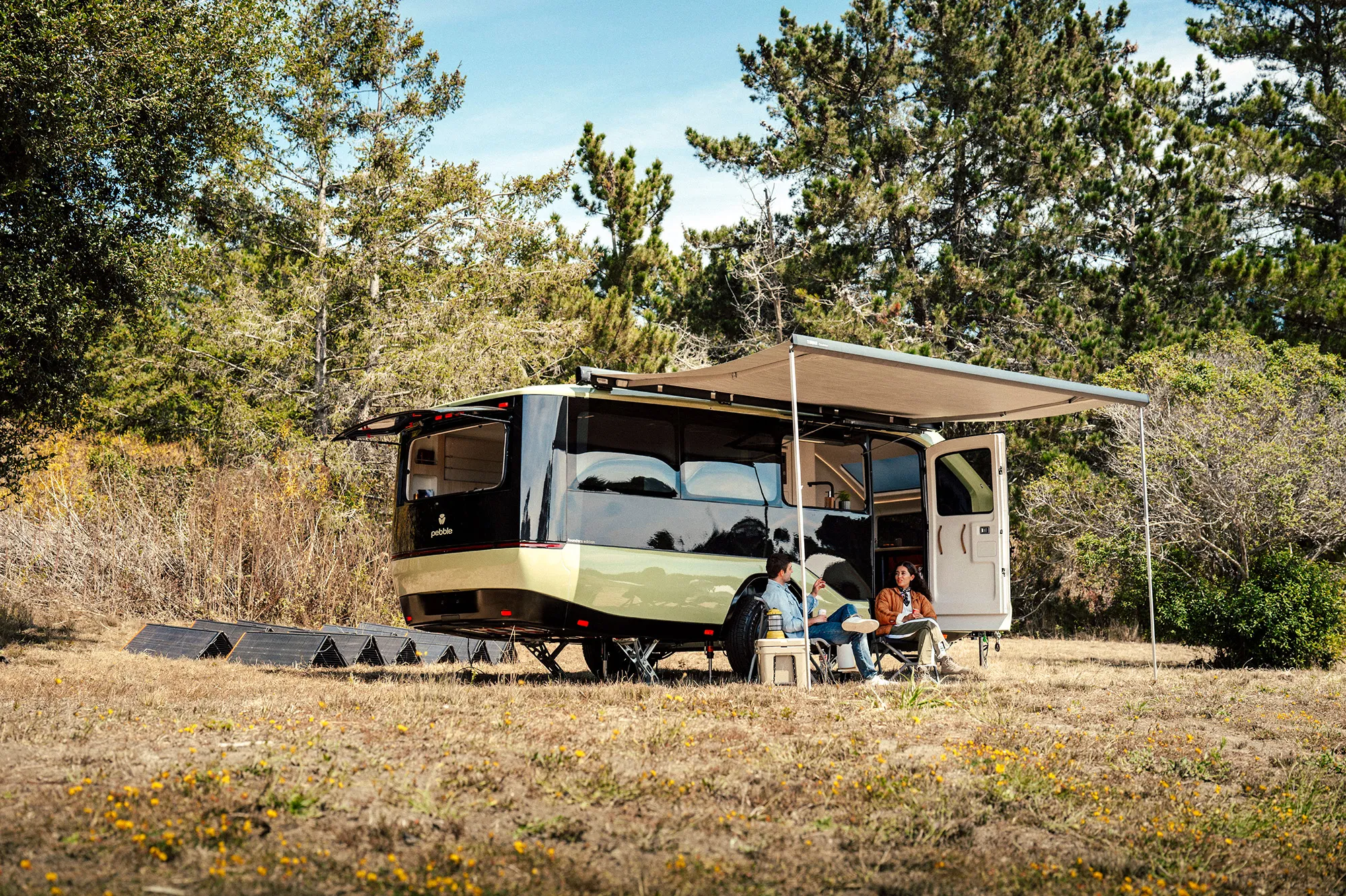 2027 Pebble Flow all-electric travel trailer at a campsite with powered awning extended