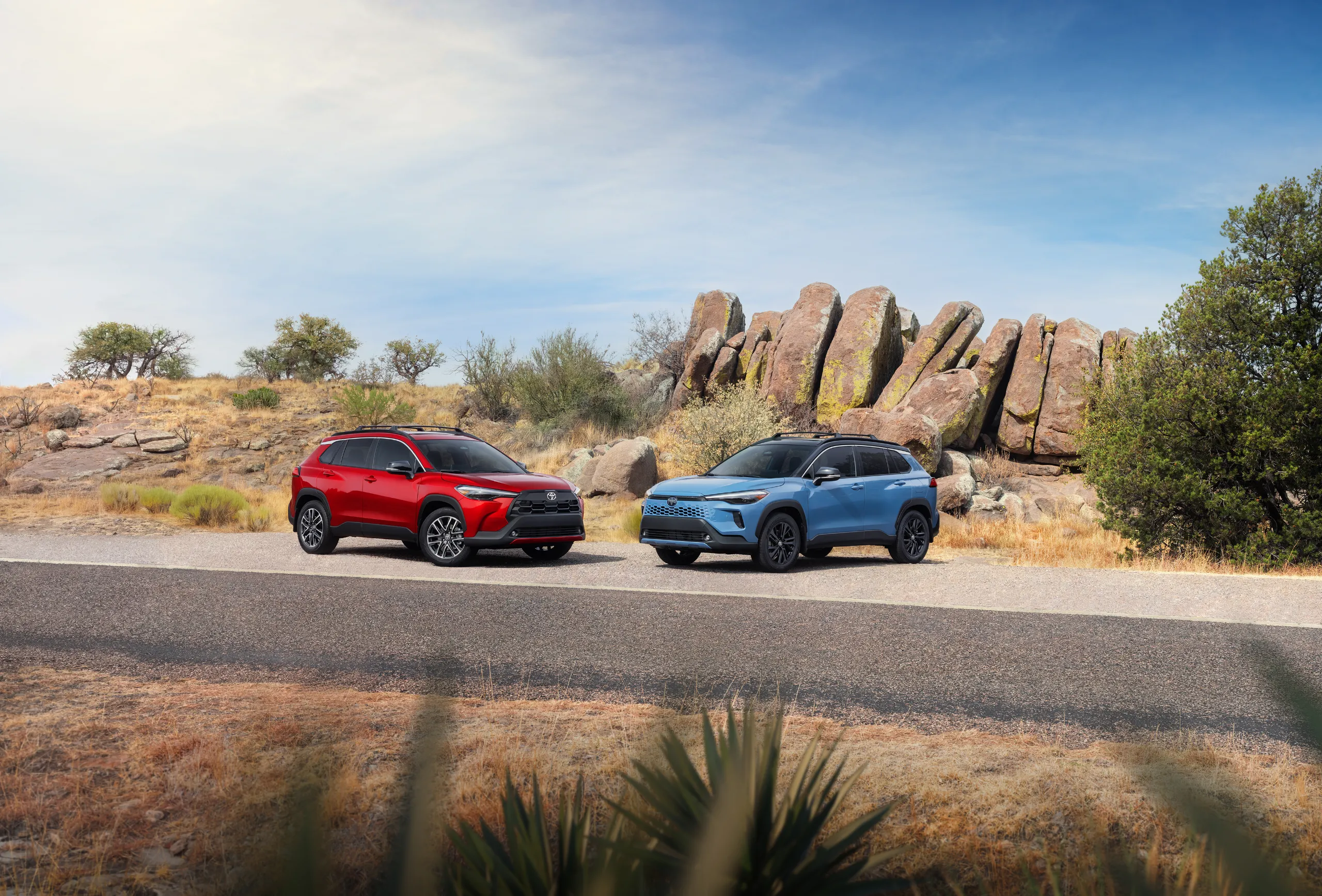 Red and blue 2027 Toyota Corolla Cross models parked in front of desert rock formations