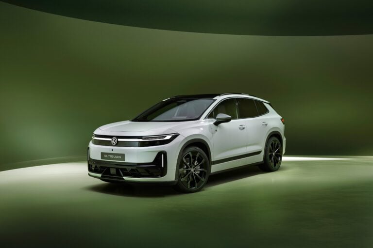 White Volkswagen ID. Tiguan electric SUV, front three-quarter view in a green studio